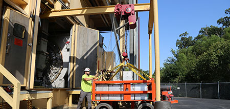 Crane technician performing a rated load test on a 10 ton overhead crane and hoist.