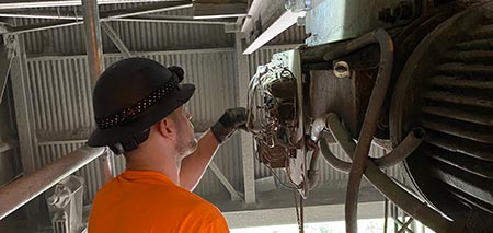 Tri-State Overhead Crane technician performing service on electrical components of a monorail tractor drive.