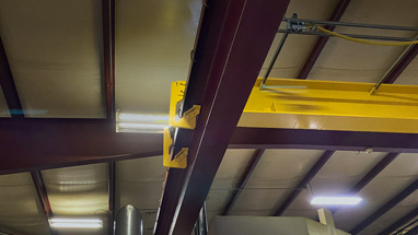 Overhead bridge crane with an anti-jump catch to keep crane from coming off the rails.